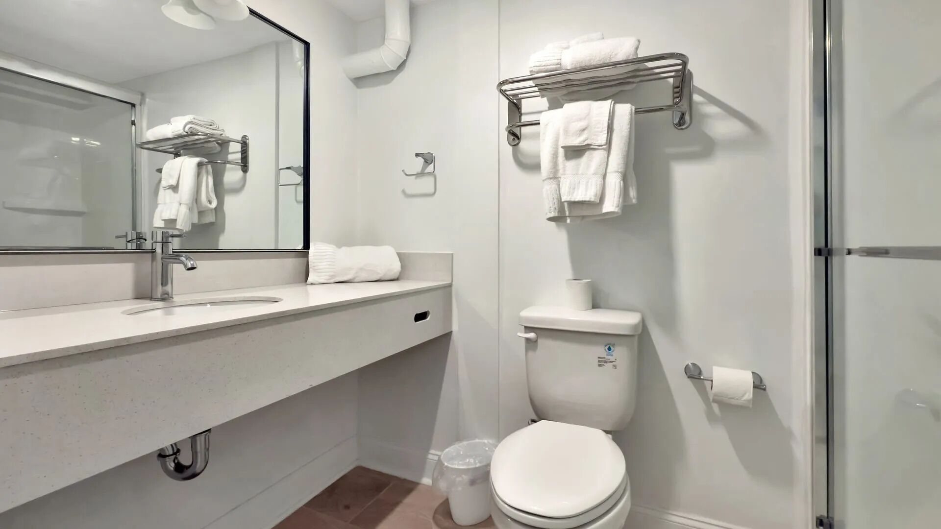 A modern bathroom with a large mirror, a sink, a toilet, and a shower area.