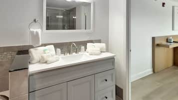 A modern bathroom with a double sink vanity, a large mirror, and a glass shower enclosure.