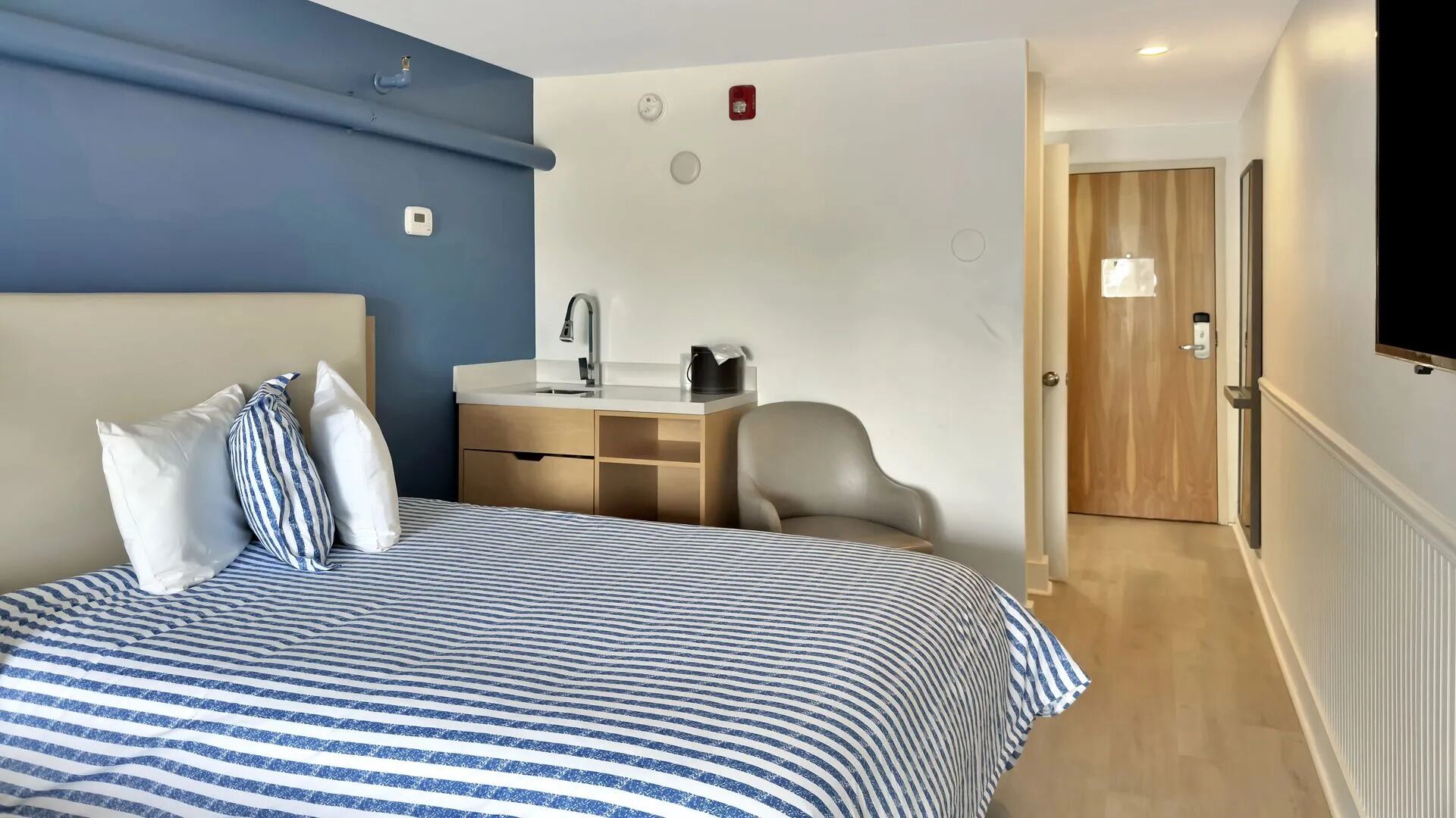 Una habitación de hotel con cama, escritorio, silla y televisión.