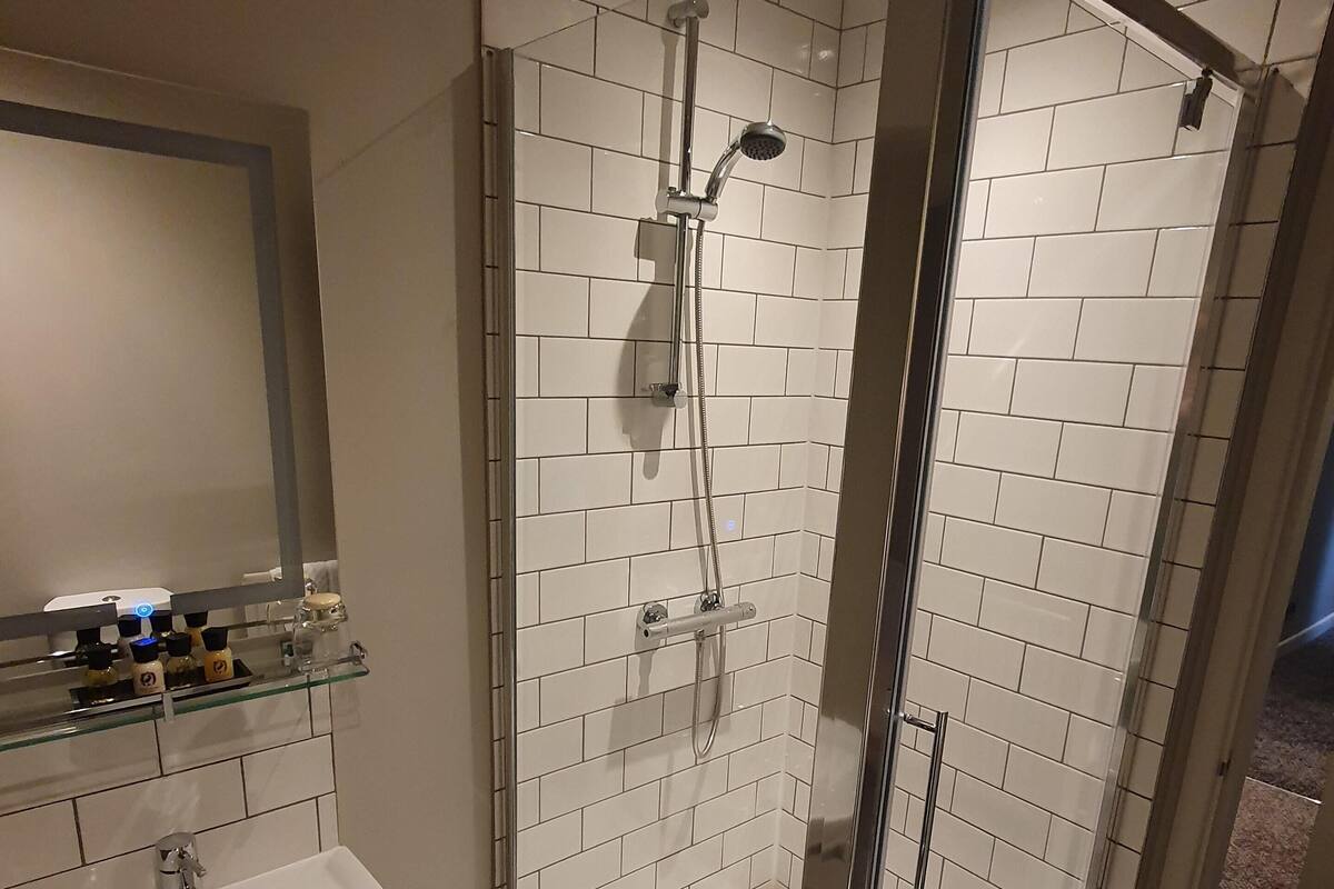 A modern bathroom with a glass-enclosed shower, a white sink, and a mirror above the sink.