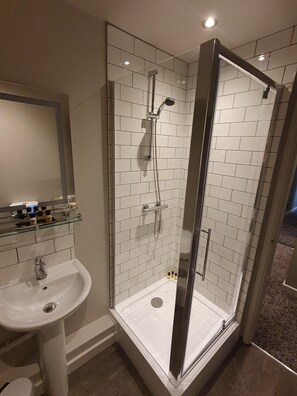 A modern bathroom with a glass-enclosed shower, a white sink, and a mirror above the sink. - The Coach and Horses (Hexham)