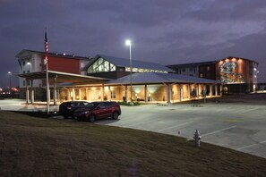 A hotel with a covered outdoor area, a parking lot, and a building with a mural. - Homewood Suites by Hilton TechRidge Parmer @ I-35 (Austin)