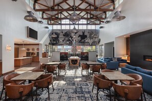 A spacious lounge area with high ceilings, exposed beams, and a variety of seating options including tables and chairs. - Homewood Suites by Hilton TechRidge Parmer @ I-35 (Austin)