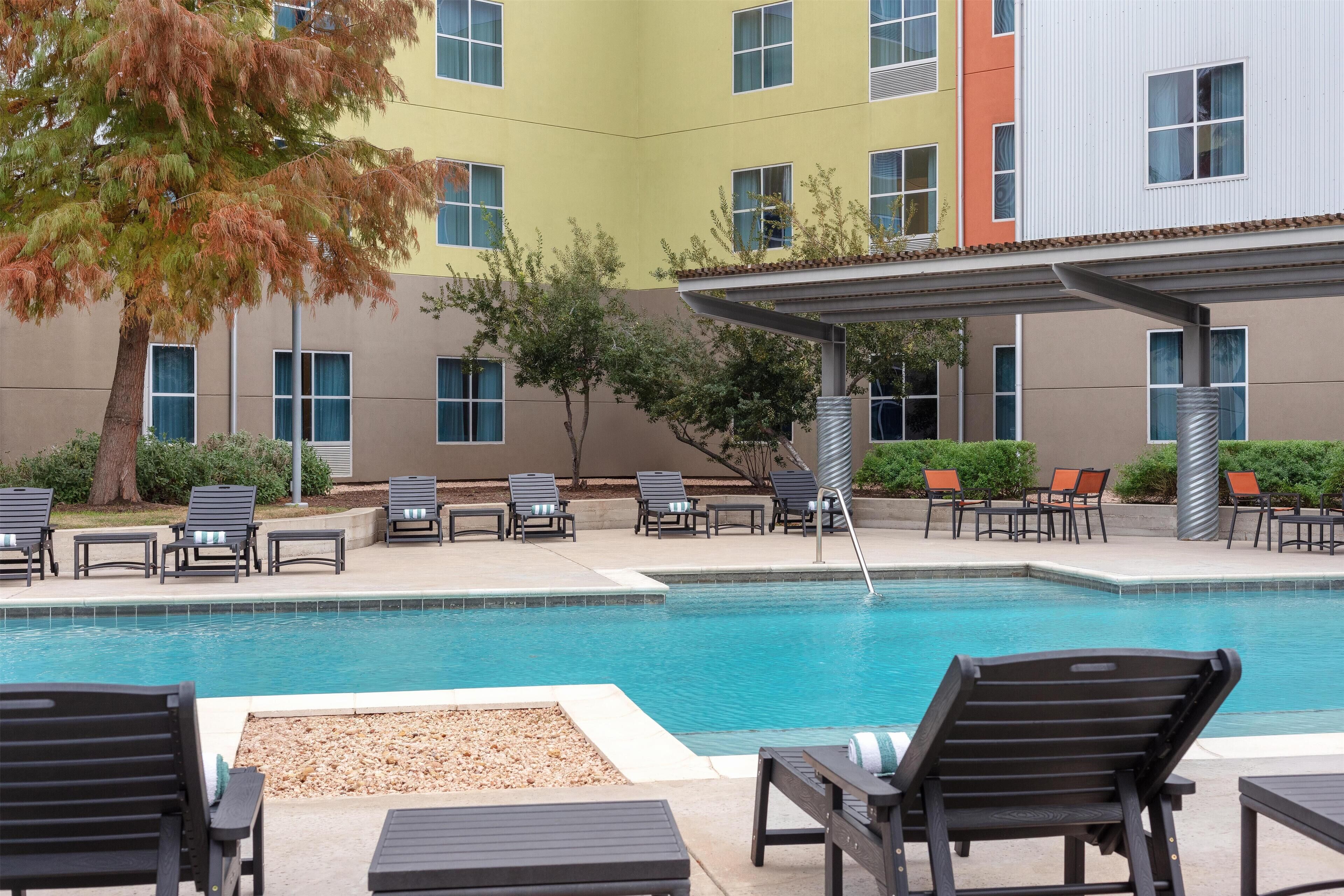 A pool area with lounge chairs and a covered seating area.