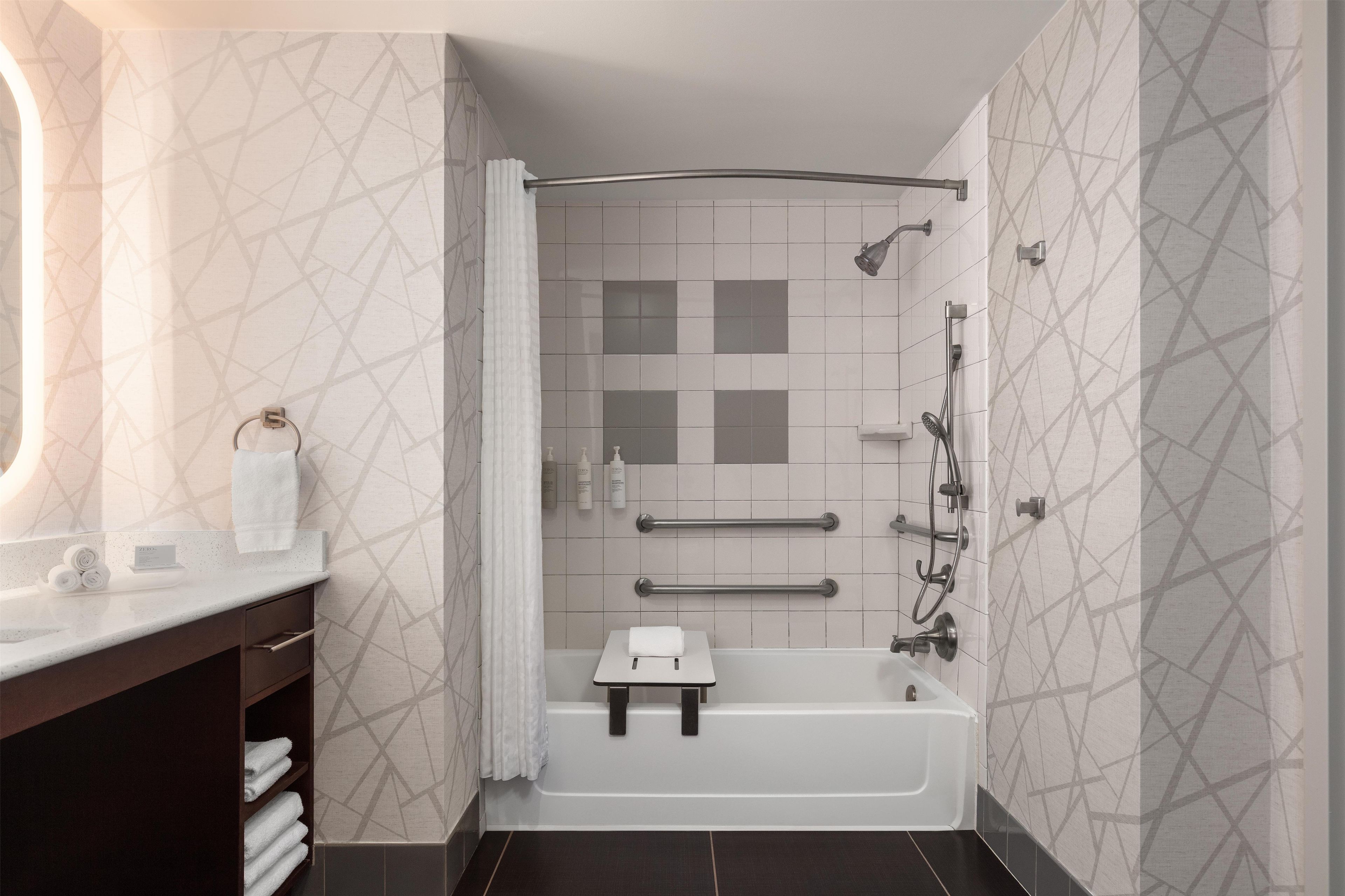 Une salle de bain moderne équipée d’une baignoire, d’une douche et d’un meuble-lavabo avec un porte-serviettes.