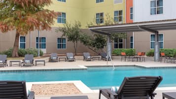 A pool area with lounge chairs and a covered seating area.