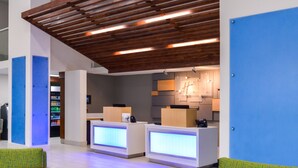 Un espace d’accueil moderne avec des poutres en bois au plafond, un mur d’accent bleu et un comptoir d’accueil doté d’un écran numérique.