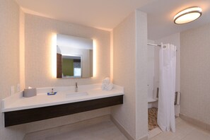 Un baño moderno con lavamanos blanco, tocador de madera oscura y cortina de ducha.
