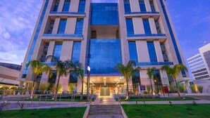 A modern building with a symmetrical facade, large windows, and a central entrance with steps. - Vista Park Sul Hplus Long Stay (Guará)