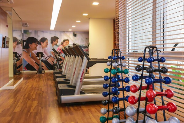 A gym with treadmills, weights, and a mirror wall. - Vista Park Sul Hplus Long Stay (Guará)