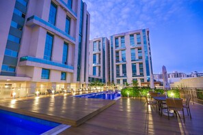 A rooftop pool area with lounge chairs and umbrellas, surrounded by modern buildings. - Vista Park Sul Hplus Long Stay (Guará)