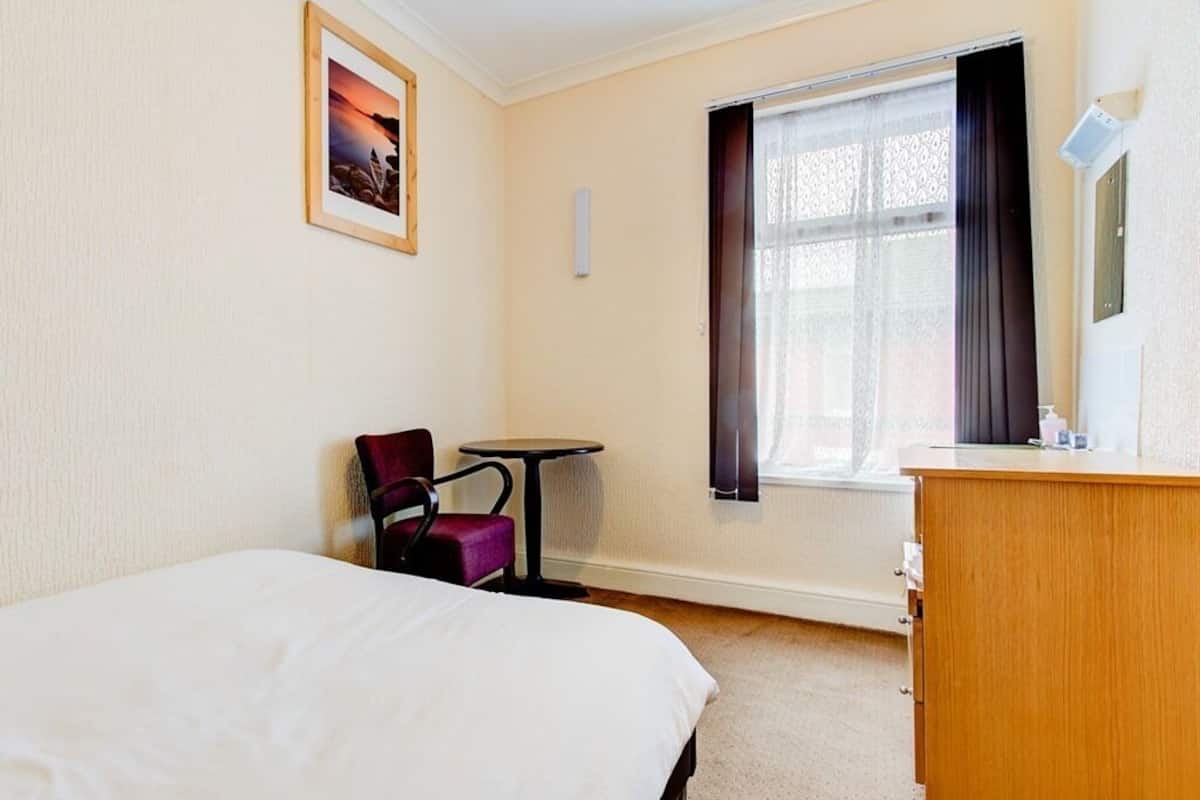 Une chambre d’hôtel avec un lit, un bureau, une chaise et une fenêtre avec des rideaux.