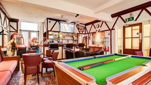 A pool table with a green felt surface, surrounded by wooden chairs and a red sofa. - Thistle Dhu Guest House (Blackpool)