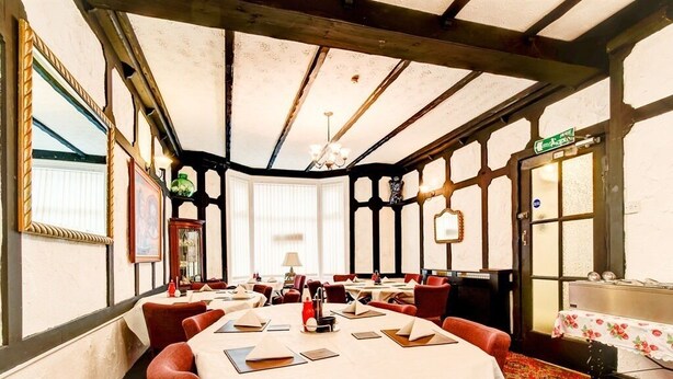 A dining area with tables set for a meal, a chandelier, and a patterned carpet. - Thistle Dhu Guest House (Blackpool)