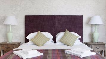 A double bed with two pillows, a striped blanket, and two bedside tables with lamps.