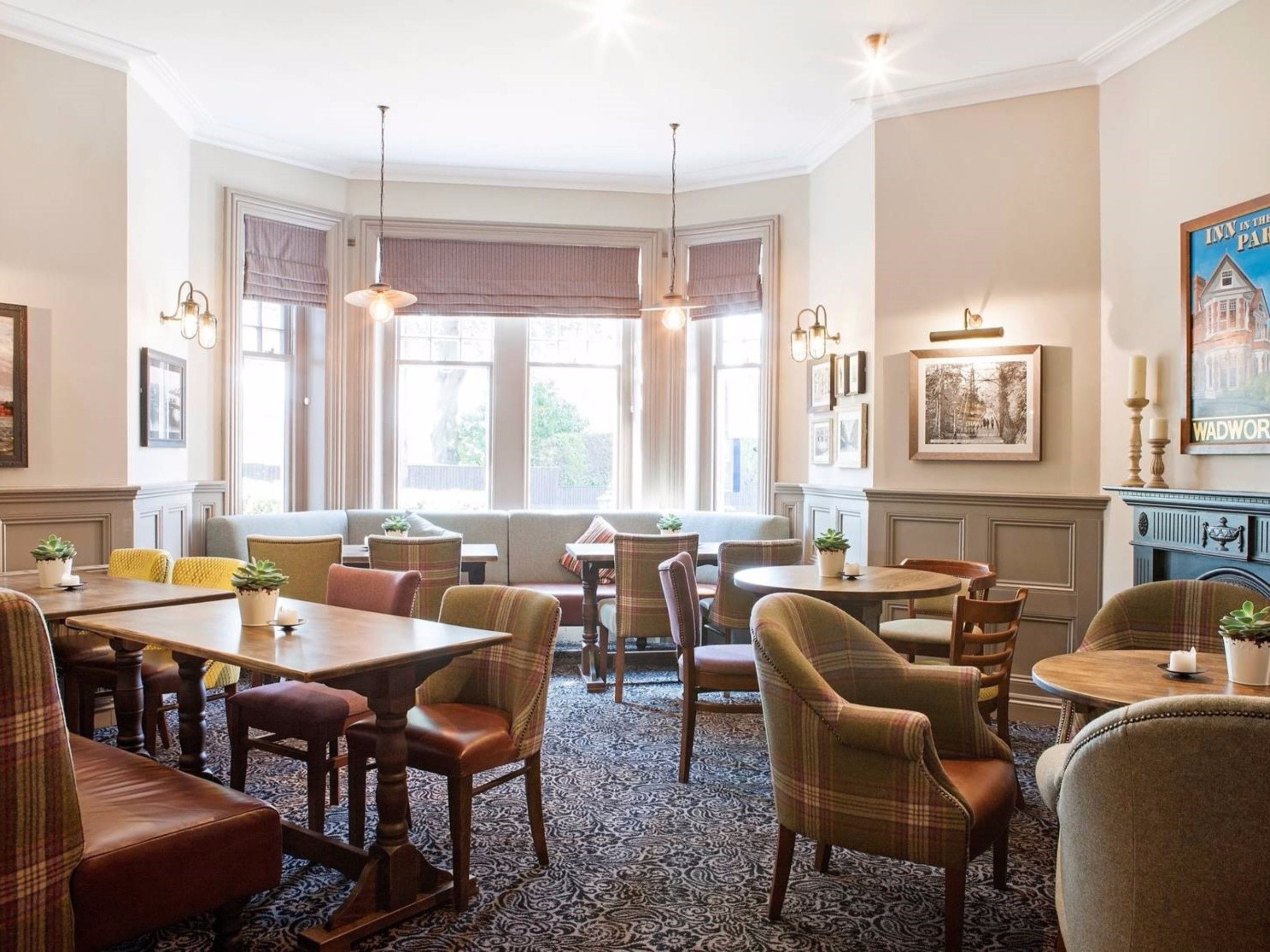 A traditional inn with a cozy seating area, multiple dining tables, and a fireplace.