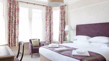 Een hotelkamer met een bed, een stoel, een tafel en gordijnen.