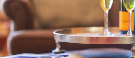A close-up of a magazine with colorful pages, a metal tray with a glass of champagne, and a bottle of wine.