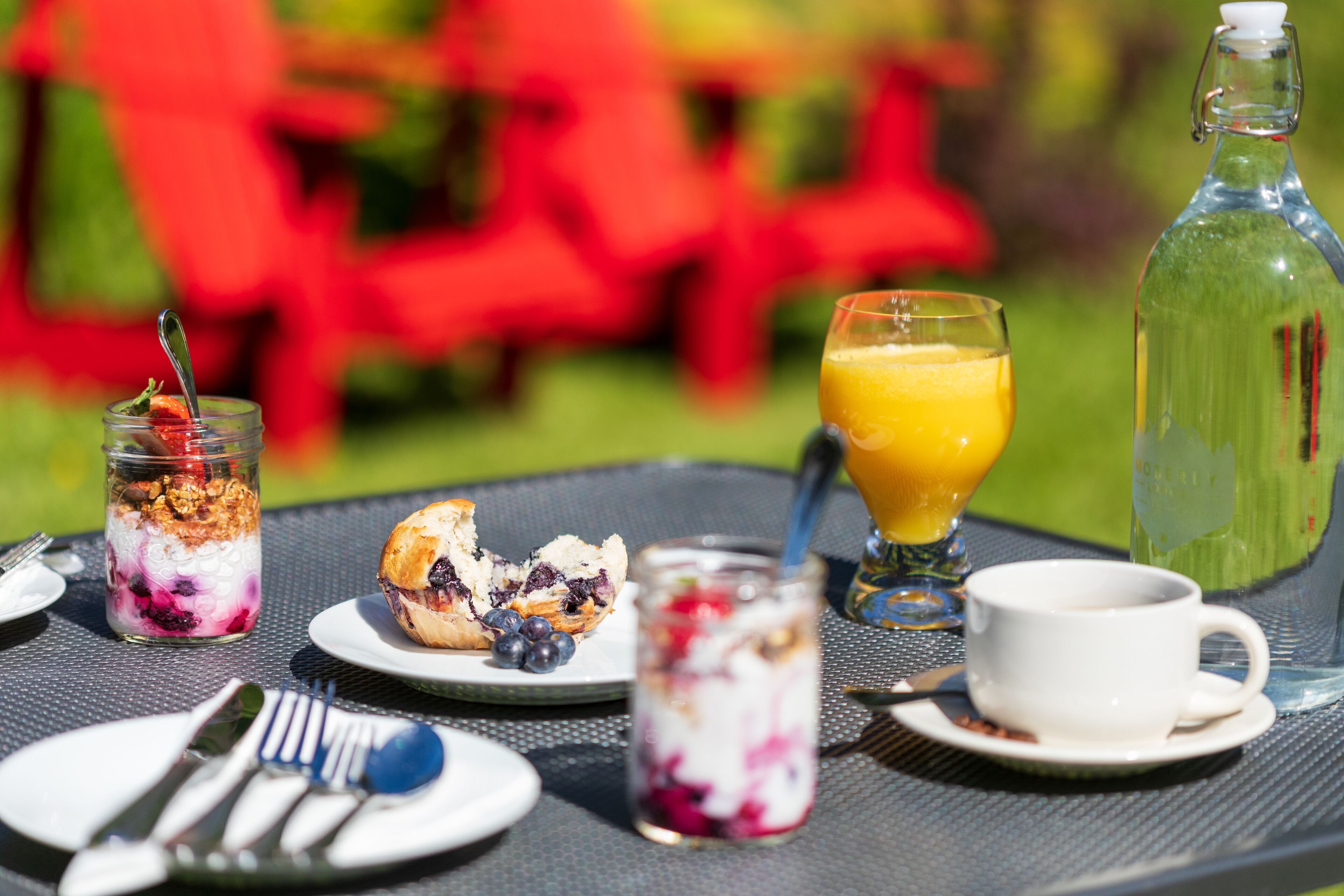 A breakfast setting with a glass of orange juice, a bottle of water, and a cup on a table.