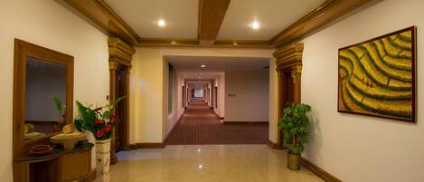 Un pasillo de hotel con piso pulido, detalles de madera y un cuadro grande en la pared.