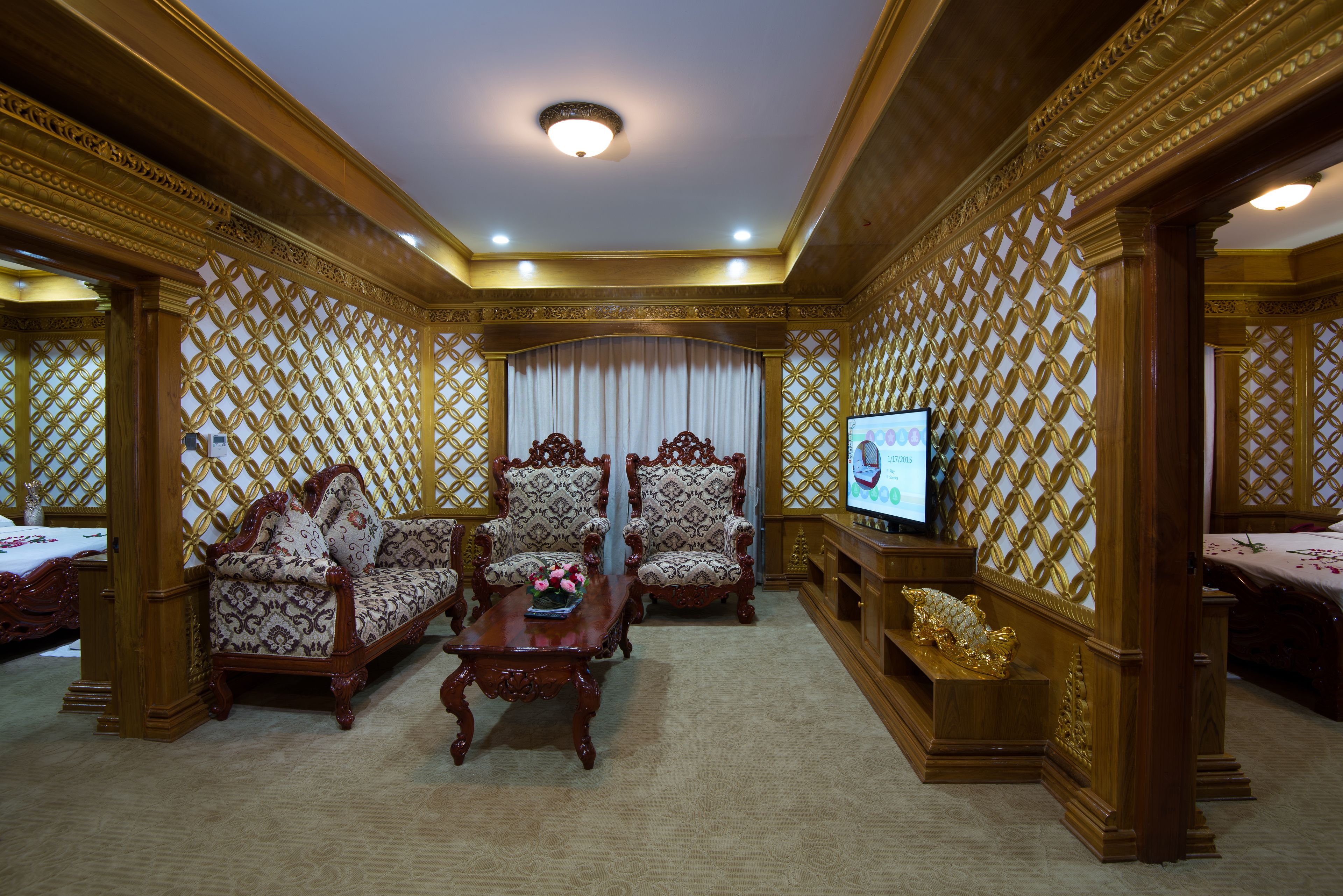 A luxurious room with ornate wooden furniture, a television, and a decorative screen.