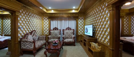 A luxurious room with ornate wooden furniture, a television, and a decorative screen.