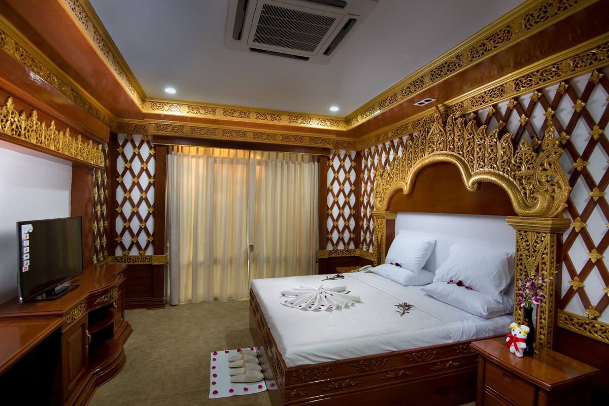 A hotel room with a wooden bed, a television, and a decorative wall.