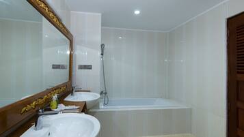 Un baño con dos lavamanos, una bañera y un espejo grande con marco decorativo.