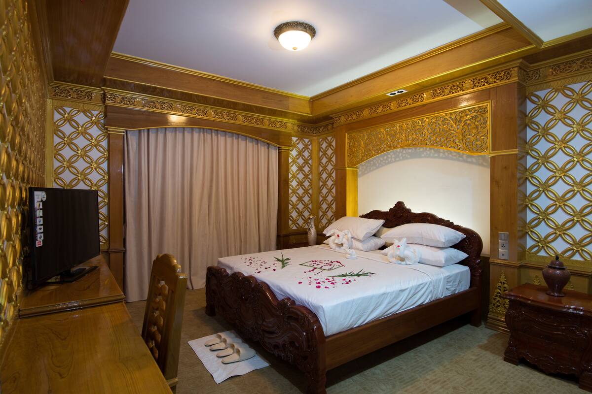 A hotel room with a wooden bed, a television, and a desk.