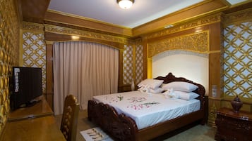A hotel room with a wooden bed, a television, and a desk.