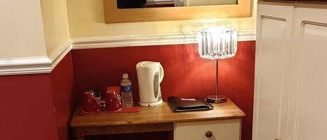A small room with a wooden desk, a chair, a mirror, a cabinet, and a red carpet.