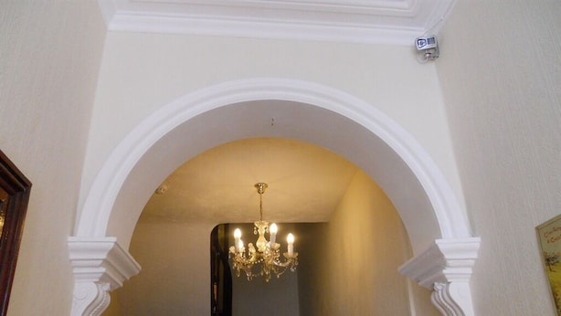 An arched doorway with a chandelier, white columns, and a staircase in the background. - All Seasons Guest House (Great Yarmouth)