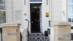 A guest house entrance with a sign listing amenities like all rooms, tea facilities, and free WiFi. - All Seasons Guest House (Great Yarmouth)