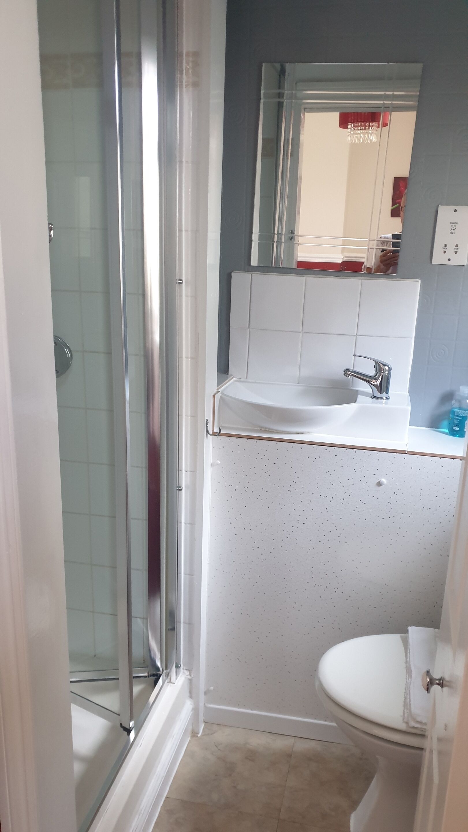 A bathroom with a glass shower enclosure, a sink with a faucet, and a toilet.