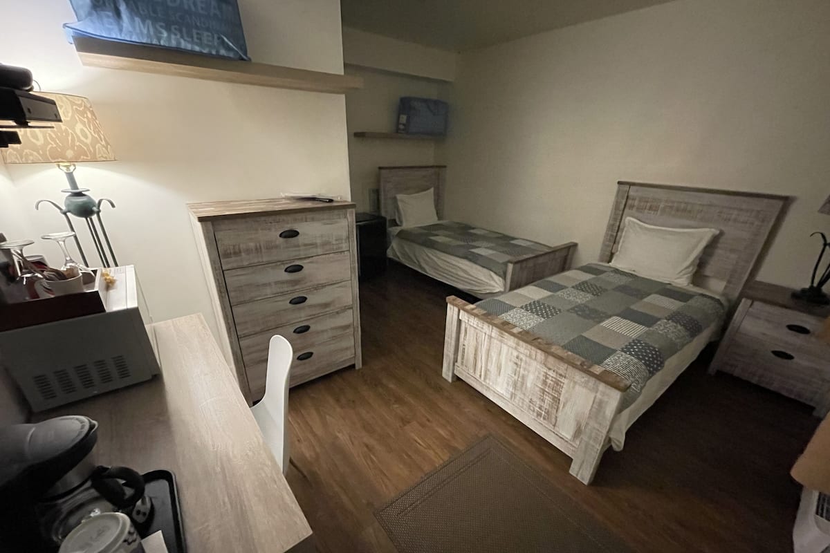 Un dormitorio pequeño y acogedor con una cama de madera, un escritorio, una silla y un aparador.