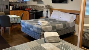 A compact hotel room with a single bed, a small kitchenette, a dining area, and a television. - Sunset Motel (Cache Creek)