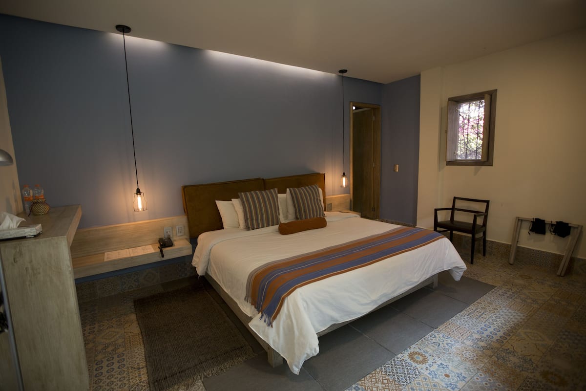 A bedroom with a large bed, bedside tables, a nightstand, a window, and a door.