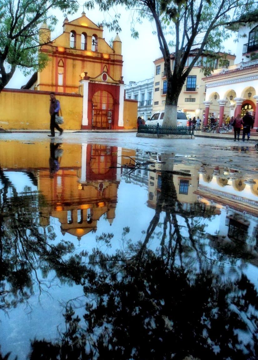 A building with a red gate and a reflection in the water.
