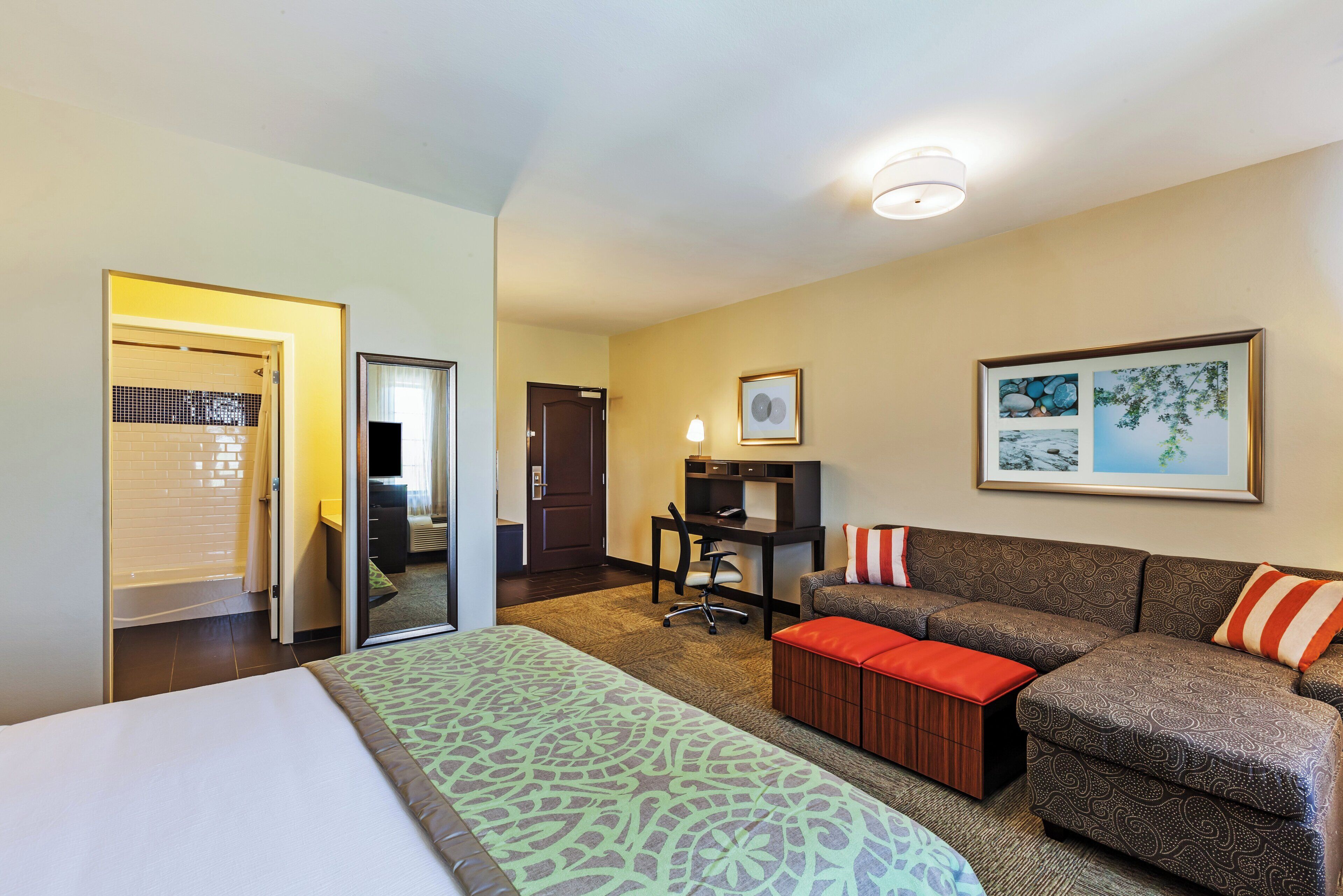 A hotel room with a bed, a sofa, a desk, and a bathroom.