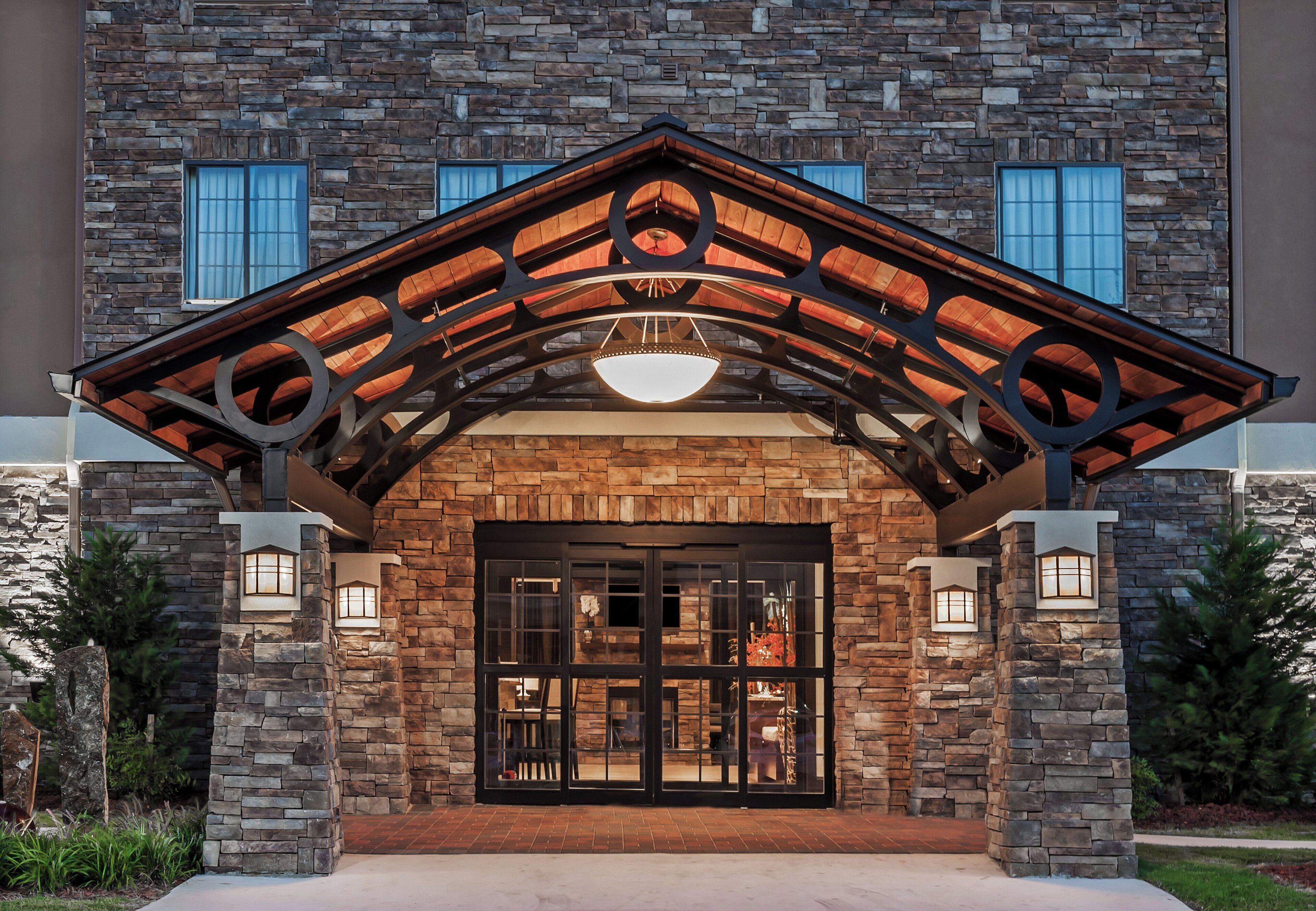 A building with a stone facade, a wooden entrance canopy, and a large glass door.