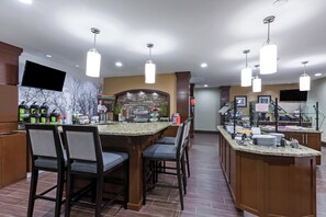 Een hotelbar met een achtergrond van een stenen muur, diverse zithoeken en een buffet.