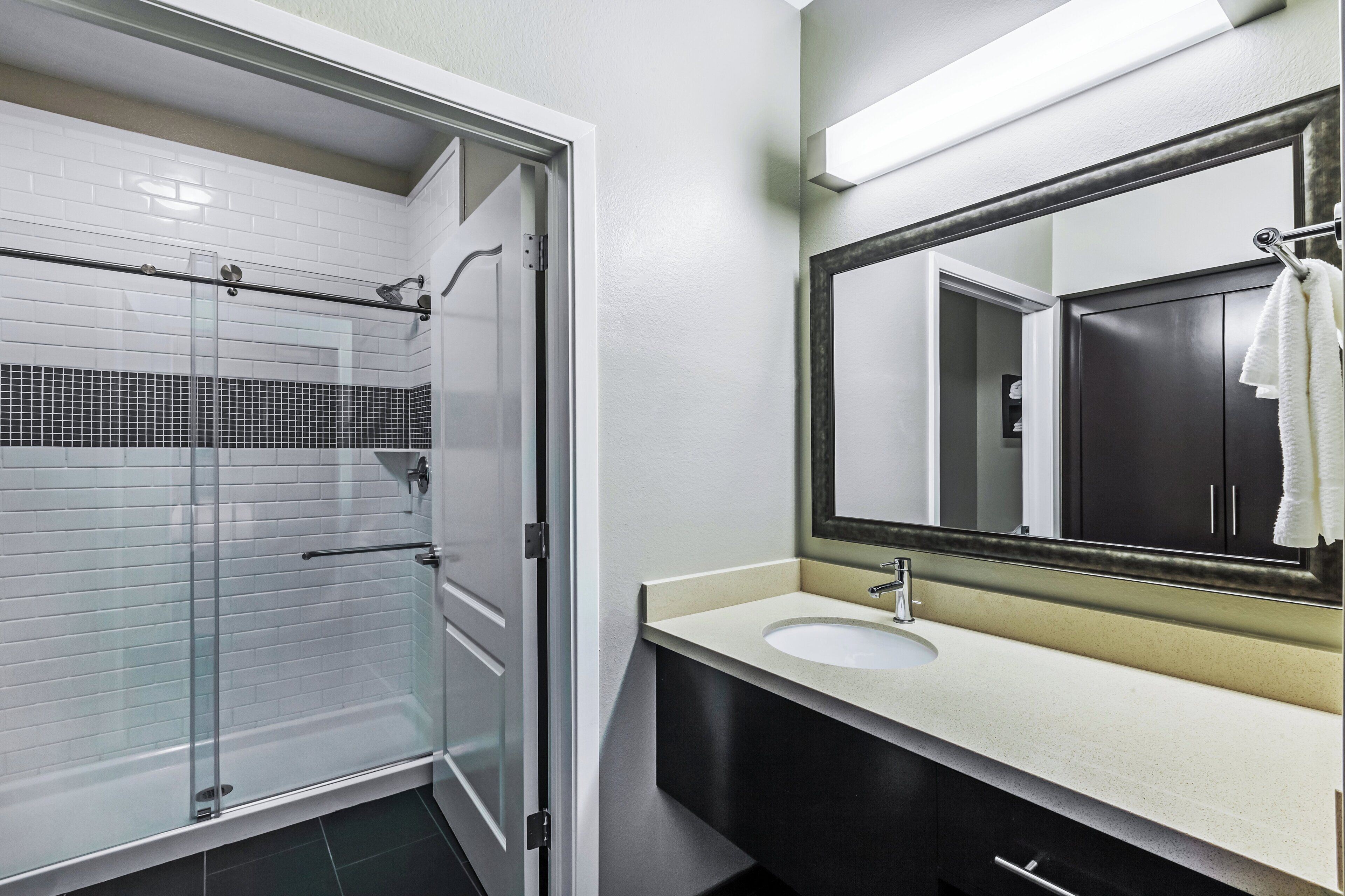 Une salle de bain avec une douche à parois de verre, un lavabo avec un miroir et un porte-serviettes.