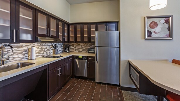 A modern kitchen with dark cabinets, stainless steel appliances, and a tiled backsplash. - Staybridge Suites Fort Worth - Fossil Creek by IHG (Fort Worth)