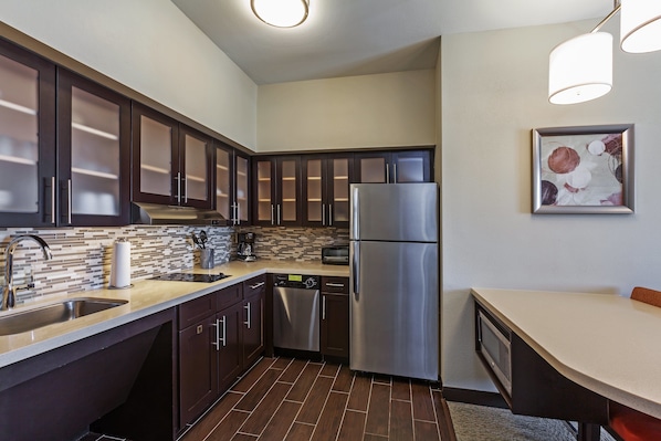 Una cocina moderna con gabinetes oscuros, electrodomésticos de acero inoxidable y un salpicadero de azulejos.