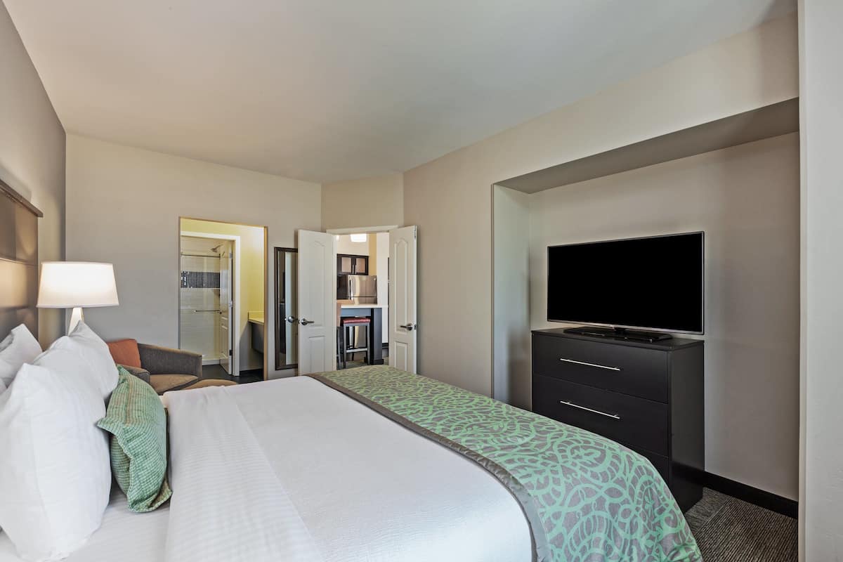 Een hotelkamer met een bed, een televisie, een bureau en een kledingkast.