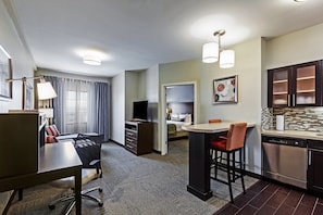 Habitación de hotel con comedor, kitchenette y dormitorio independiente.