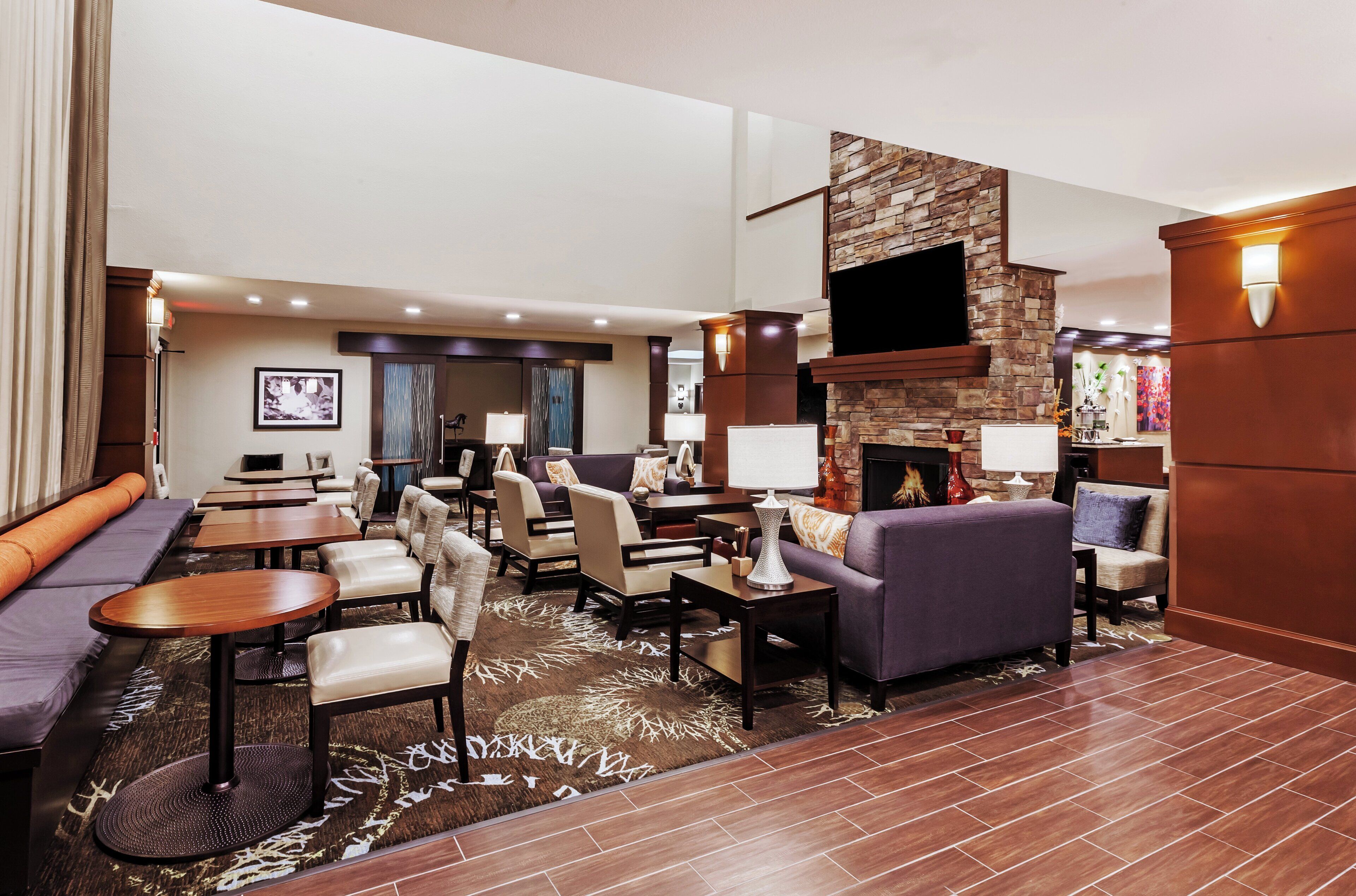 A spacious lobby with a seating area, a fireplace, and a television mounted on a stone wall.