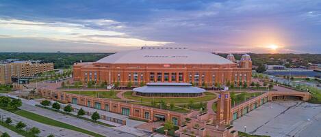 A large stadium with a dome roof and a central tower, surrounded by landscaped areas and parking.