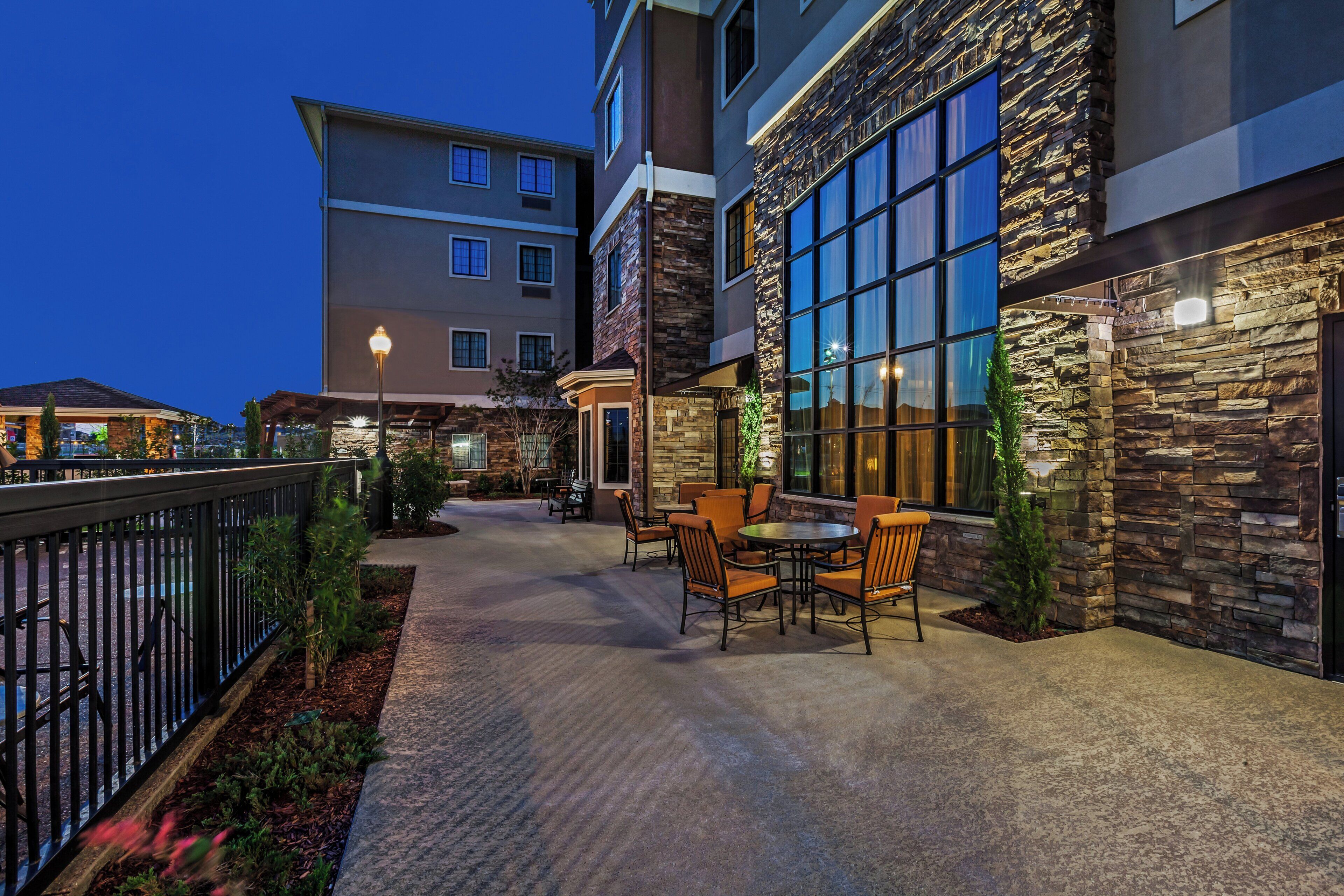 A hotel patio with outdoor seating and a stone facade.
