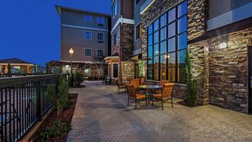 A hotel patio with outdoor seating and a stone facade.